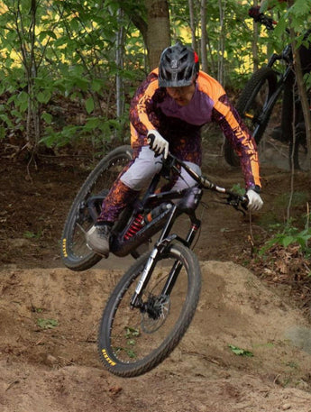 Two mountain bikers navigating a trail in a forest setting.